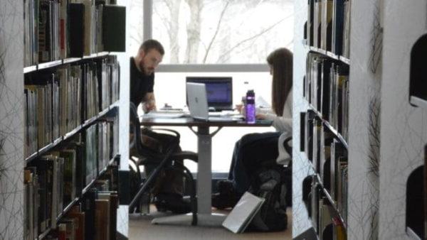 Two students studying at a table in the library